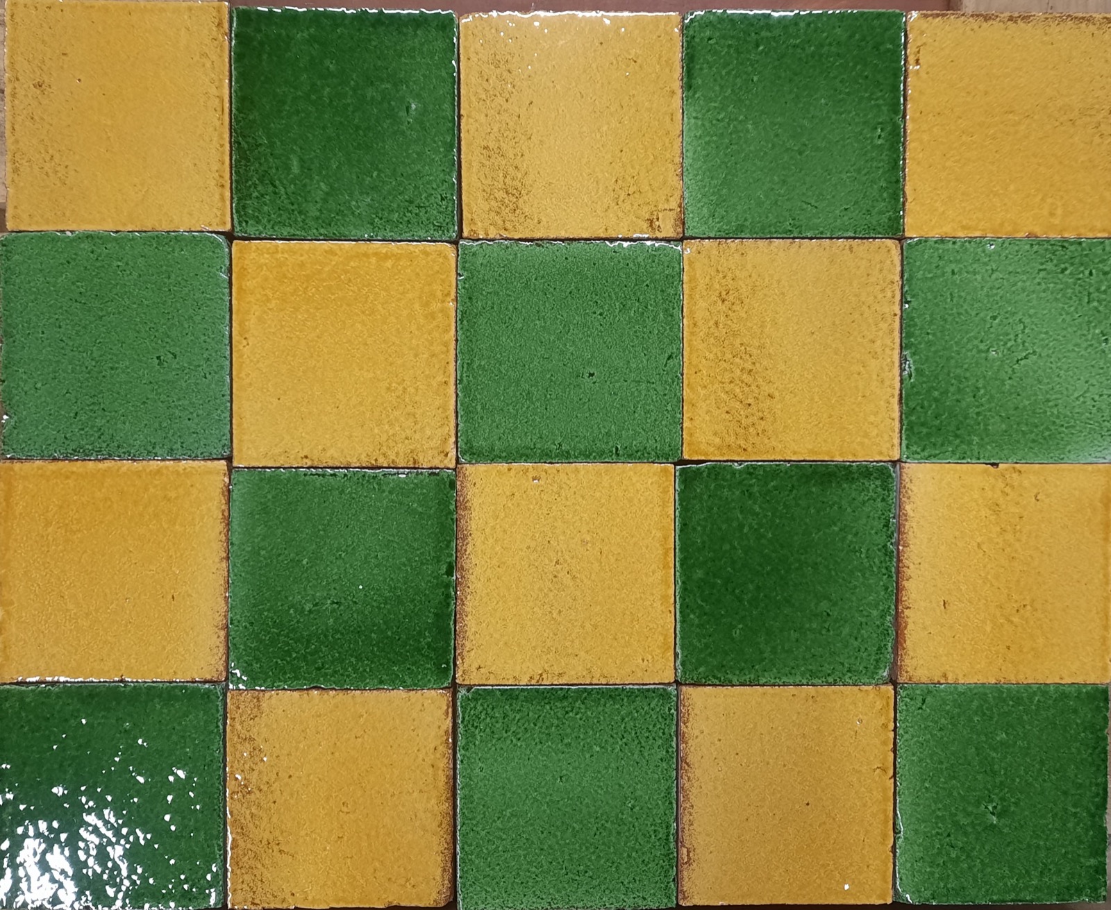 Pavement en carreaux émaillés verts et jaunes, motifs alternés, dans un logis médiéval.