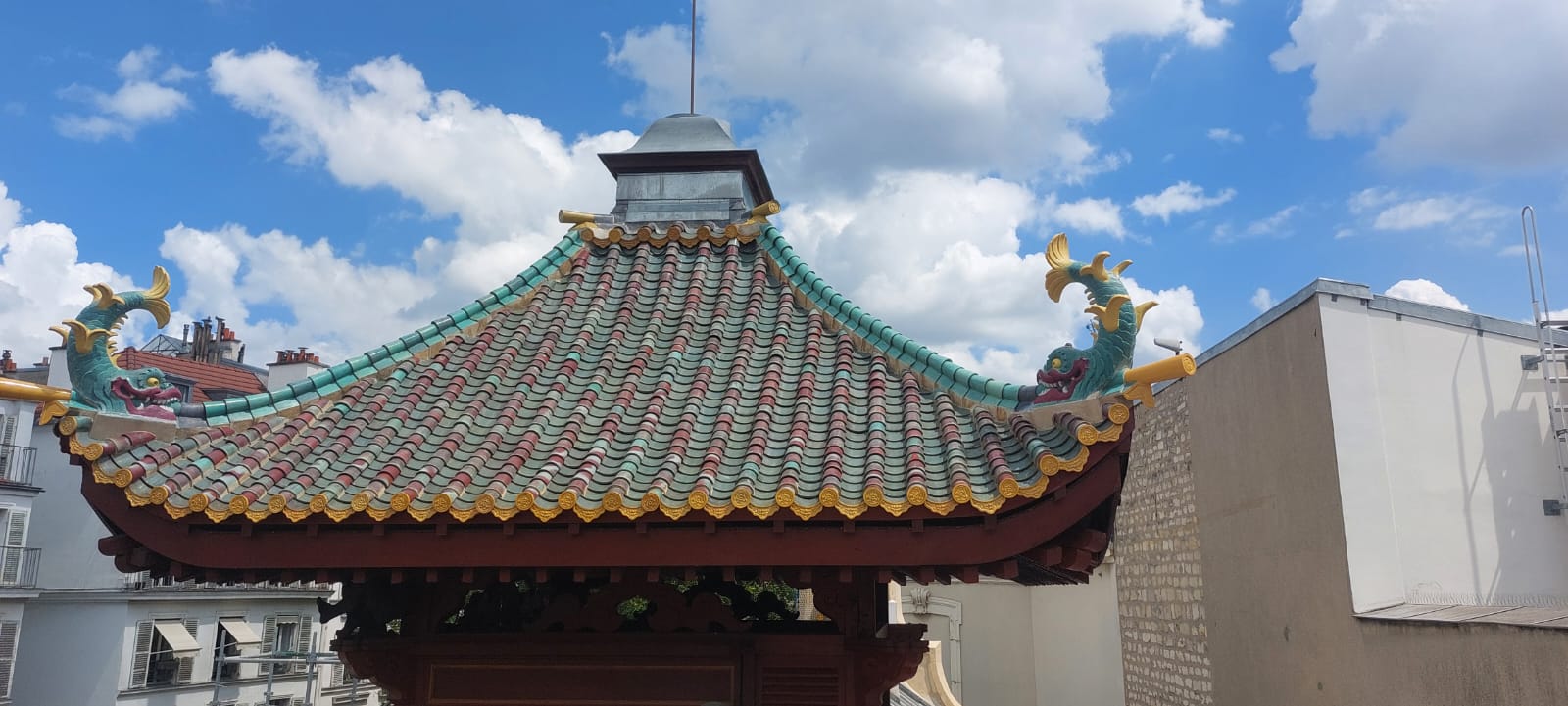 Toiture de La Pagode à Paris : tuiles vernissées vertes et rouges, ornements dorés et dragons aux extrémités du faîtage.